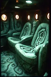 Midjourney generated image using SREF code Moldshift: A row of green reclining chairs in a dark room.