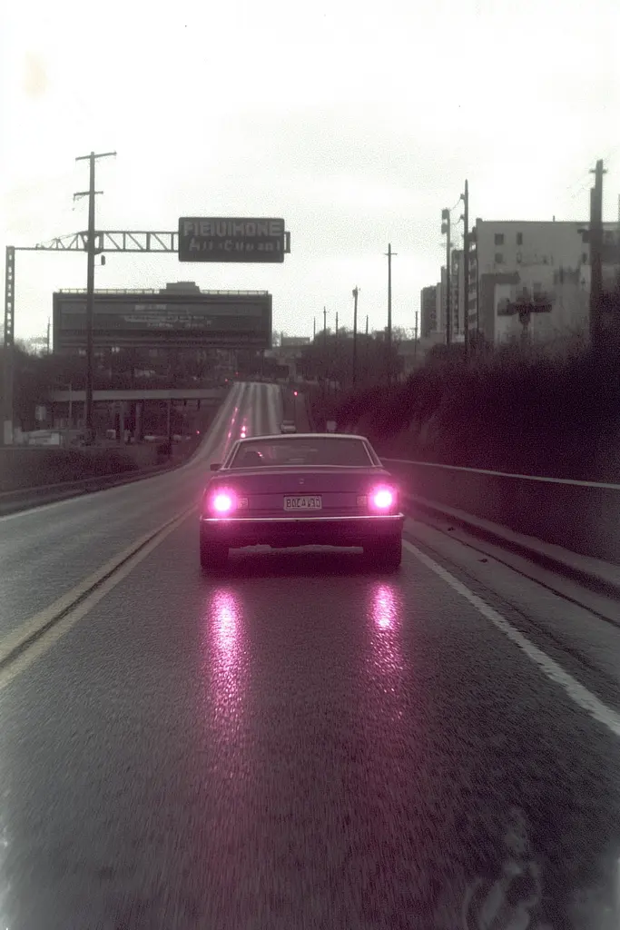 Midjourney generated image using SREF code Pastel Phantasm: A car driving down a wet road in the rain.