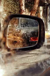 Midjourney generated image using SREF code Rustlight: A car is reflected in the rear view mirror of a car.