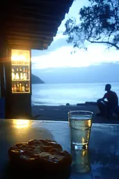 Midjourney generated image using SREF code Haloed Spectres: A glass of water sitting on top of a table next to a pizza.