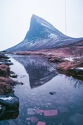 Midjourney generated image using SREF code Cyan Flux: A mountain is reflected in the water of a stream.