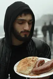 Midjourney generated image using SREF code Hushframe: A man in a black hoodie holding a plate of food.