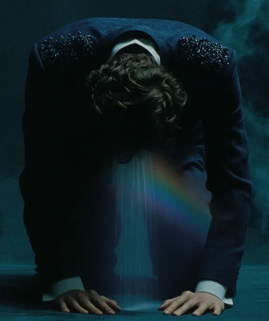Midjourney generated image using SREF code Gossamer Gaze, Ominous Alienscape, Ethereal Echoes: A man in a suit with a rainbow in the background.