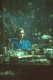 Midjourney generated image using SREF code Blue Velvet: A woman sitting at a table in a dark room.