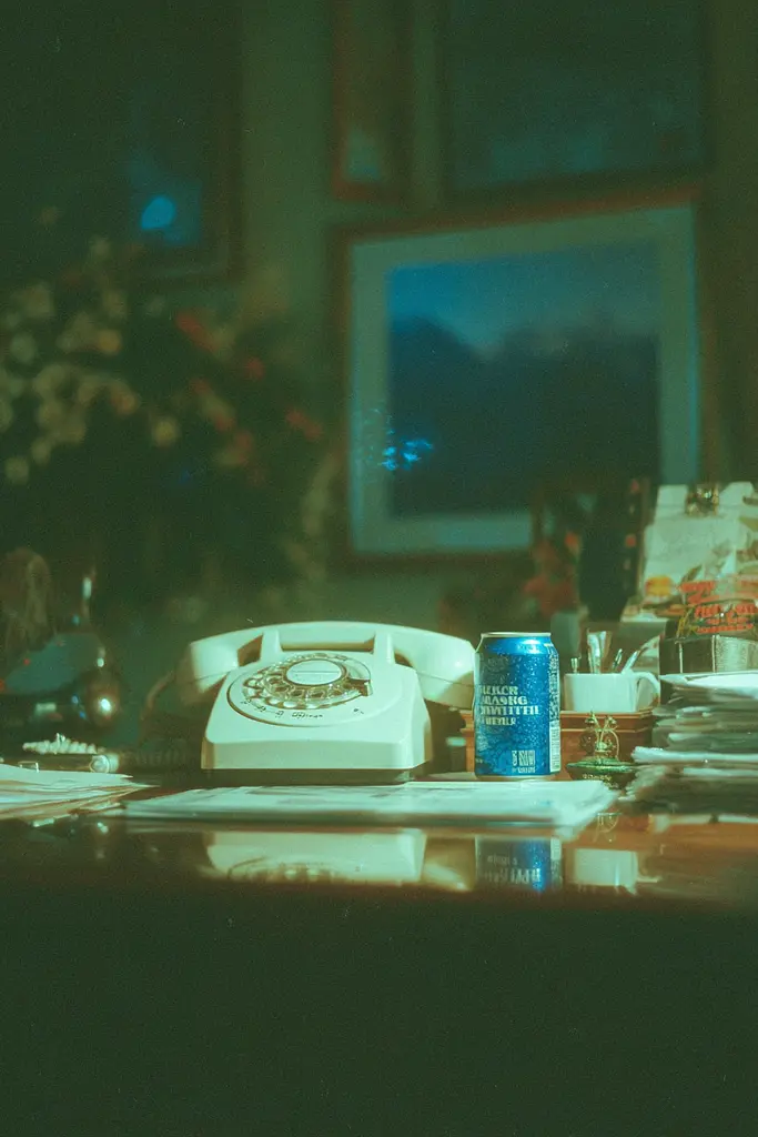 Midjourney generated image using SREF code Blue Velvet: A can of beer sitting on top of a desk next to a telephone.