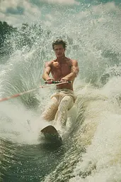 Midjourney generated image using SREF code Velvetenigma: A shirtless man riding a wake board on top of a wave.