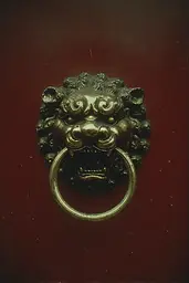 Midjourney generated image using SREF code Nebuloom: A brass lion head knocker on a red door.