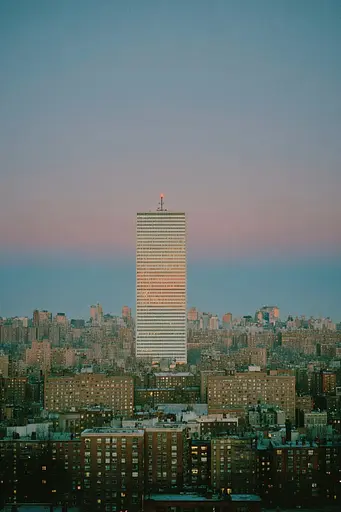 Midjourney generated image using SREF code Hushed Loomlight: A tall building in the middle of a city at dusk.