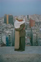 Midjourney generated image using SREF code Hushed Loomlight: A man and woman hugging on top of a building.