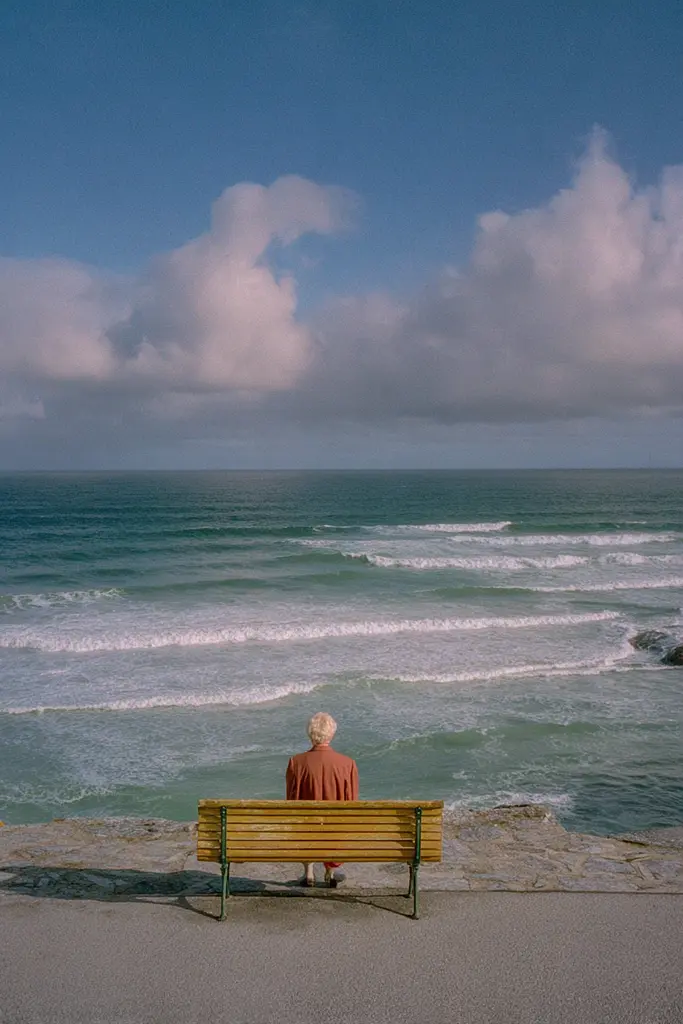 Midjourney generated image using SREF code Hushed Loomlight: A man sitting on a bench looking out at the ocean.