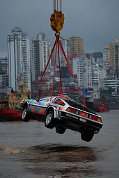Midjourney generated image using SREF code Pyrognome: A car being lifted from the water by a crane.