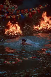 Midjourney generated image using SREF code Plushgrim: A man swimming in a body of water next to a fire.