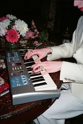 Midjourney generated image using SREF code GlimmerDial: A woman in a white suit playing a keyboard.