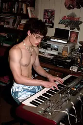 Midjourney generated image using SREF code GlimmerDial: A shirtless man sitting at a keyboard in a room.