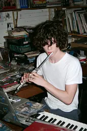 Midjourney generated image using SREF code GlimmerDial: A young man playing a flute in front of a keyboard.