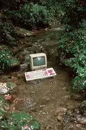 Midjourney generated image using SREF code GlimmerDial: A computer sitting in the middle of a stream.