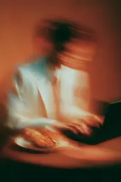 Midjourney generated image using SREF code Blurloom: A man sitting at a table using a laptop computer.
