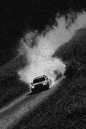 Midjourney generated image using SREF code Monoloom: A black and white photo of a car driving in the rain.