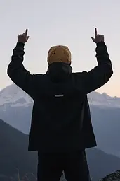 Midjourney generated image using SREF code Chiaroscuro Chronicles: A man standing on top of a mountain with his hands up.