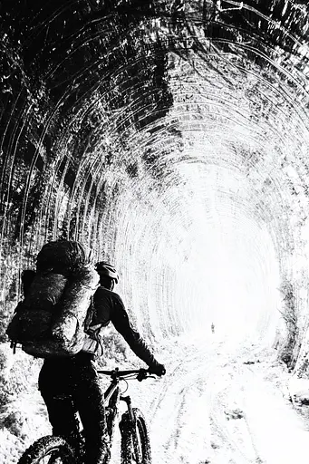 Midjourney generated image using SREF code Monochrome Shards: A man riding a bike through a tunnel in the snow.